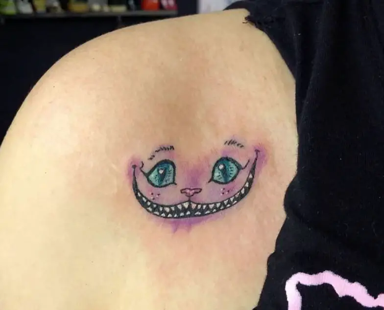 simple and small purple Cheshire Cat with blue eyes tattoo on the back