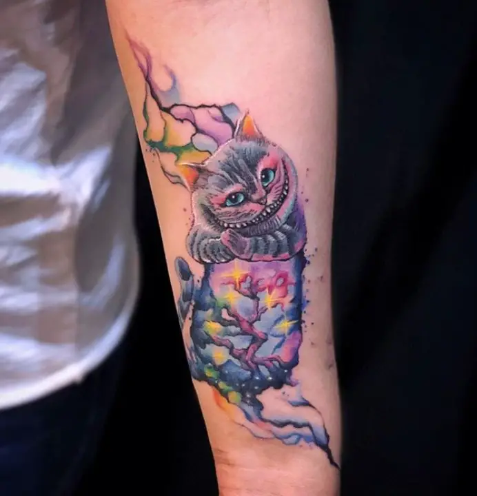 a floating colorful Cheshire Cat with its paws together and its body is designed with a colorful branch of tree tattoo on the forearm