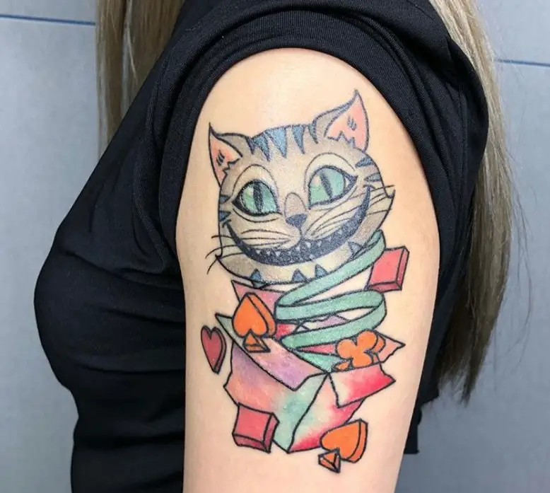 Cheshire Cat face coming out from a box with card symbols tattoo on the shoulder