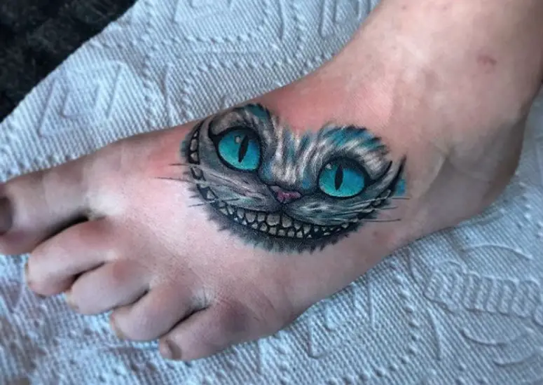 Cheshire Cat with gray, white and blue fur color and aqua blue eyes tattoo on the feet