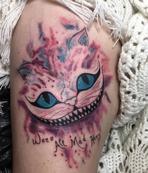 artistic Cheshire Cat with blue eyes tattoo and words 