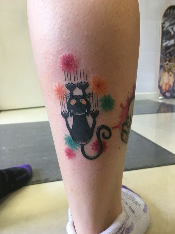 black cat with pink, orange, and green colors tattoo on the leg