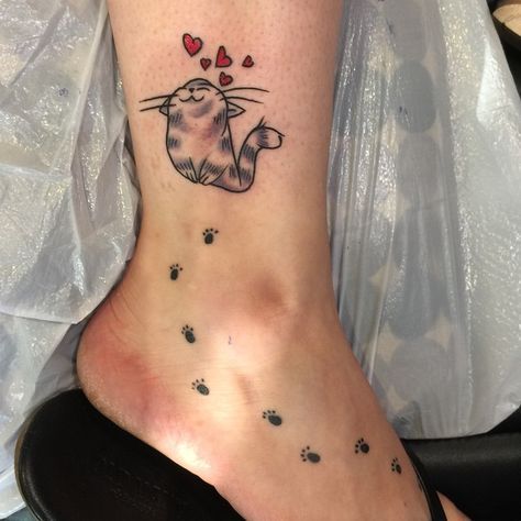 an animated happy cat with red hearts and paw prints tattoo on the leg