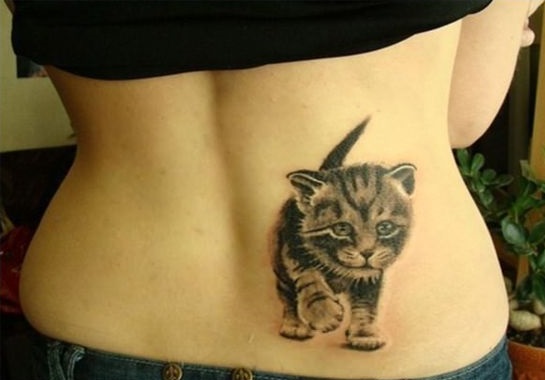 a realistic walking kitten tattoo on the back of a woman