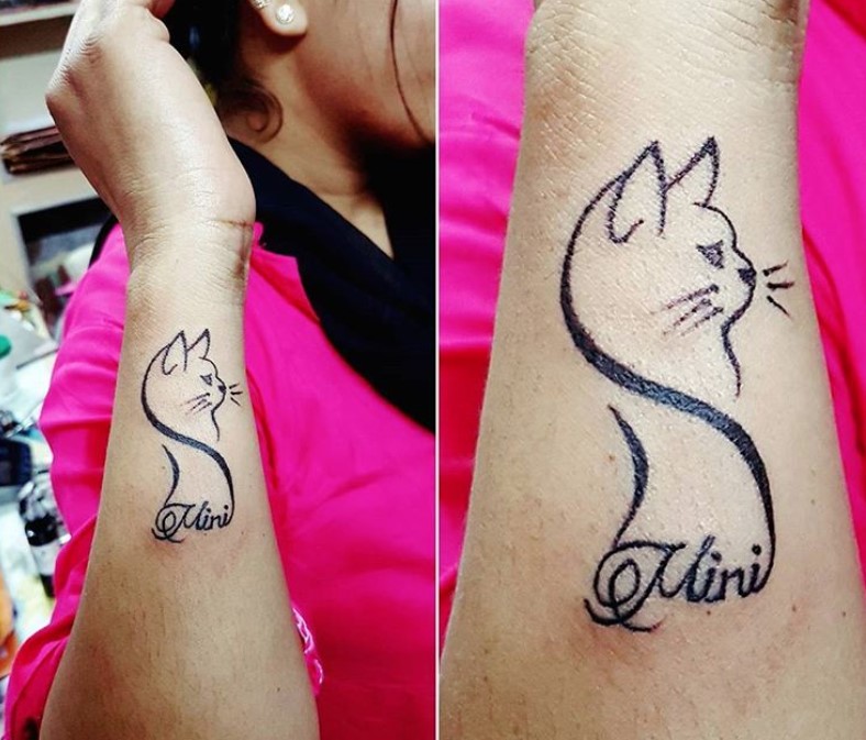 outline of a cat tattoo on the wrist