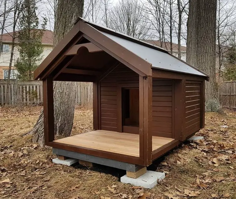A brown wooden dog house in the yard