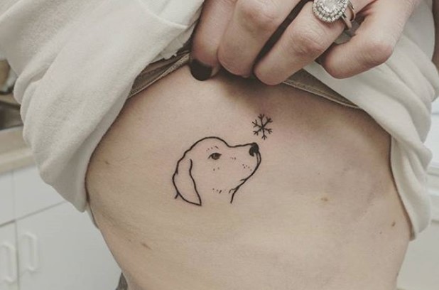 outline of dog's face with a snowflake tattoo on the side of the body
