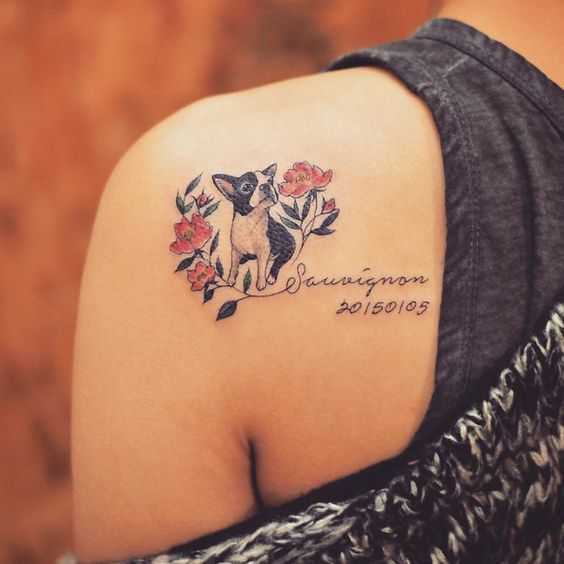 dog sitting with flowers around it and a name and date tattoo on the back