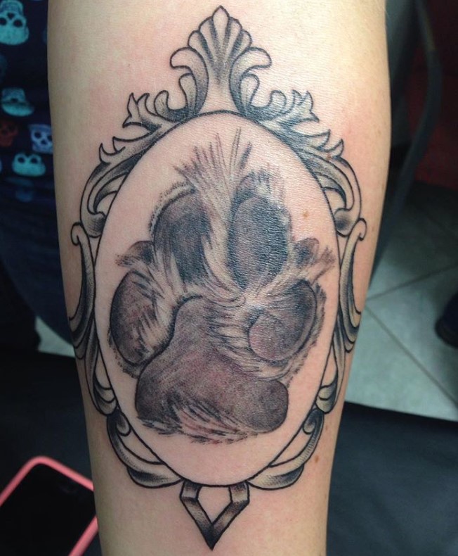 paw print inside a tattoo on the leg