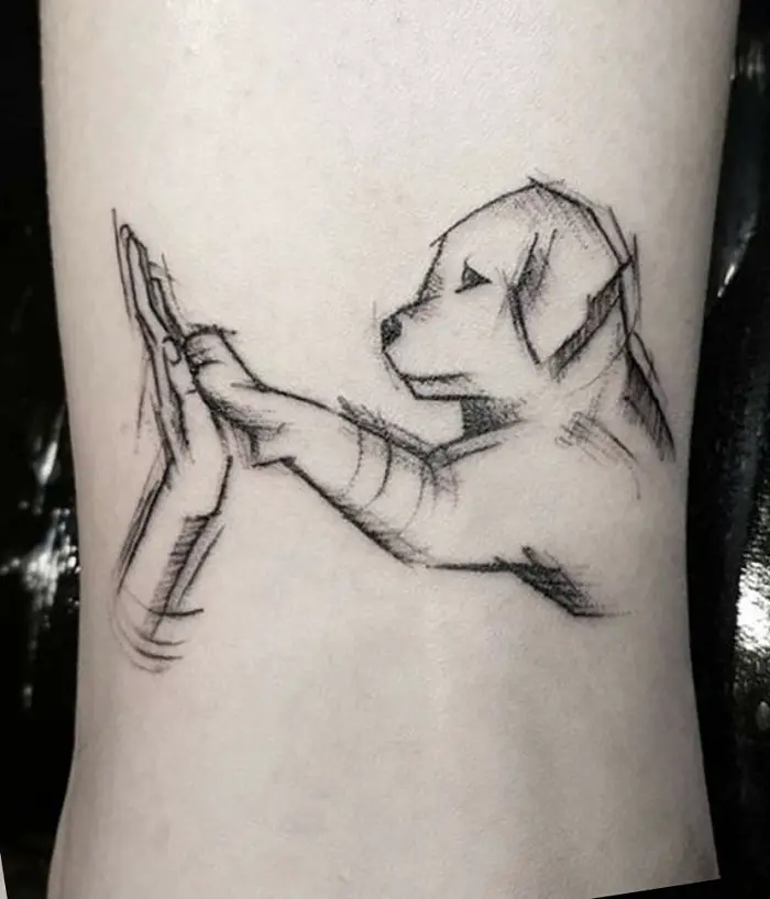 Golden Retriever puppy giving a high give sketch tattoo on the leg.
