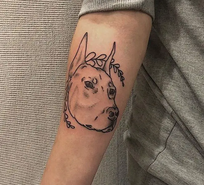outline face of a dog tattoo on the forearm