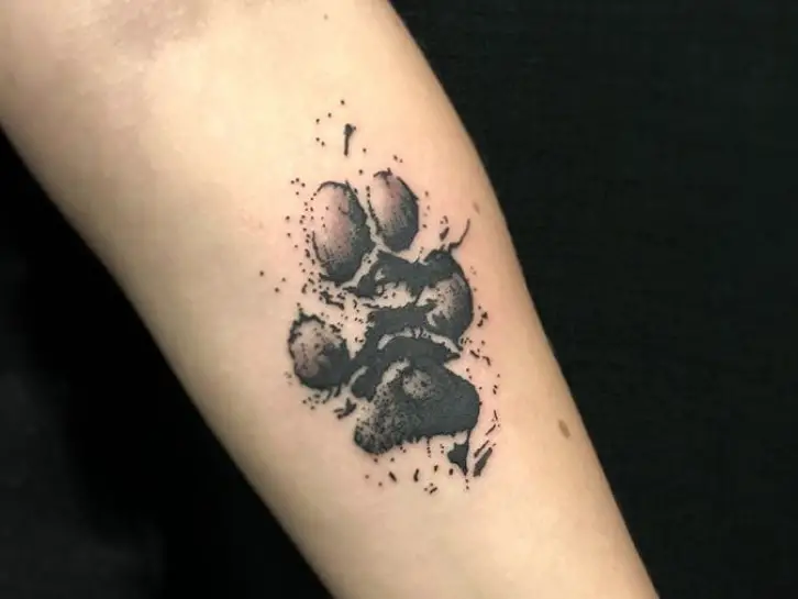 black paw print tattoo on forearm