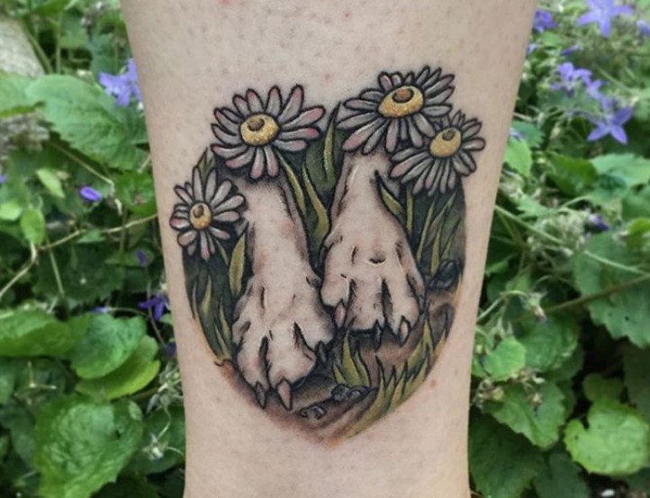 dog's hand in grass and flowers on top tattoo