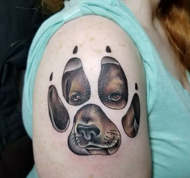dog face in paw print tattoo on the shoulder