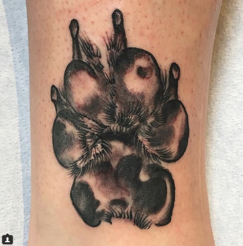 black paw print tattoo on the leg