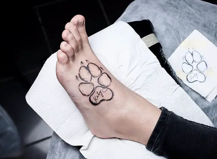 outline of paw print tattoo on foot