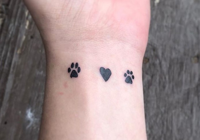 paw prints with heart in between tattoo on wrist