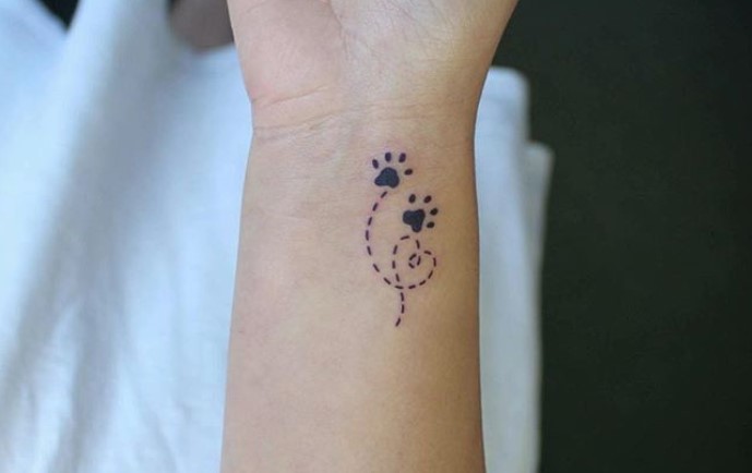 paw print with dotted line tattoo on wrist