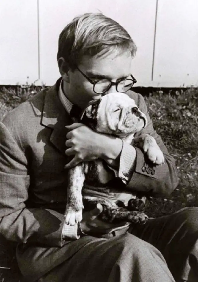 old photo of Truman Capote kissing his English Bulldog puppy