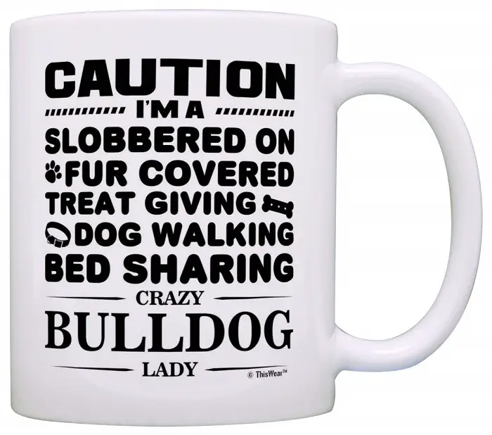 A white mug printed with - Caution I'm a slobbered on fur covered, treat giving, dog walking, bed sharing crazy bulldog lady