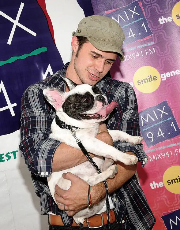 Kris Allen looking down at his French Bulldog wrapped in his arms