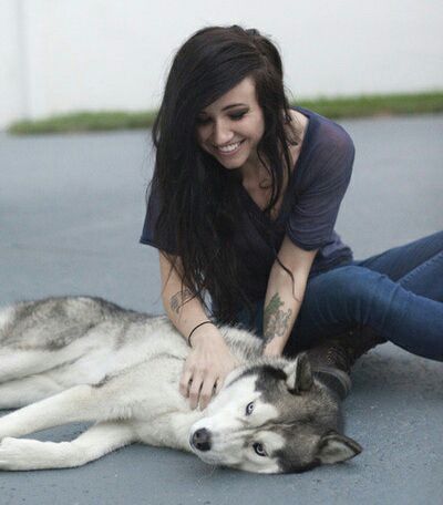 Lights (musician) sitting on the floor while rubbing her Siberian Husky
