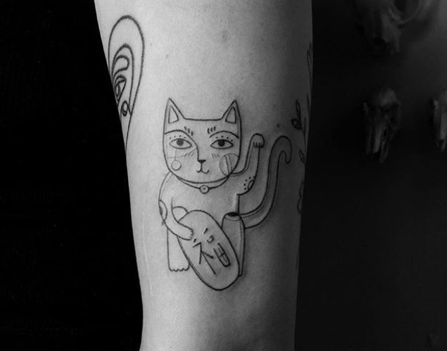 An outline of a Lucky Cat Tattoo on the forearm