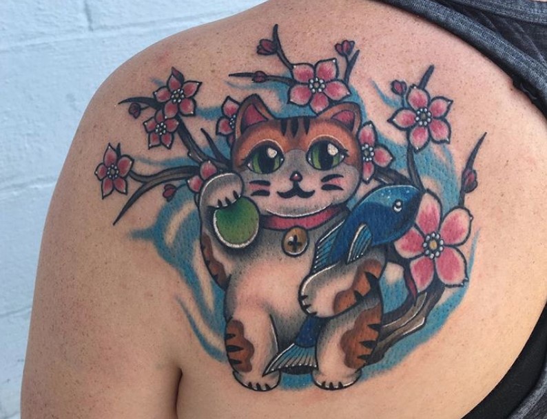 An orange Lucky Cat with sakura flowers tattoo on the back