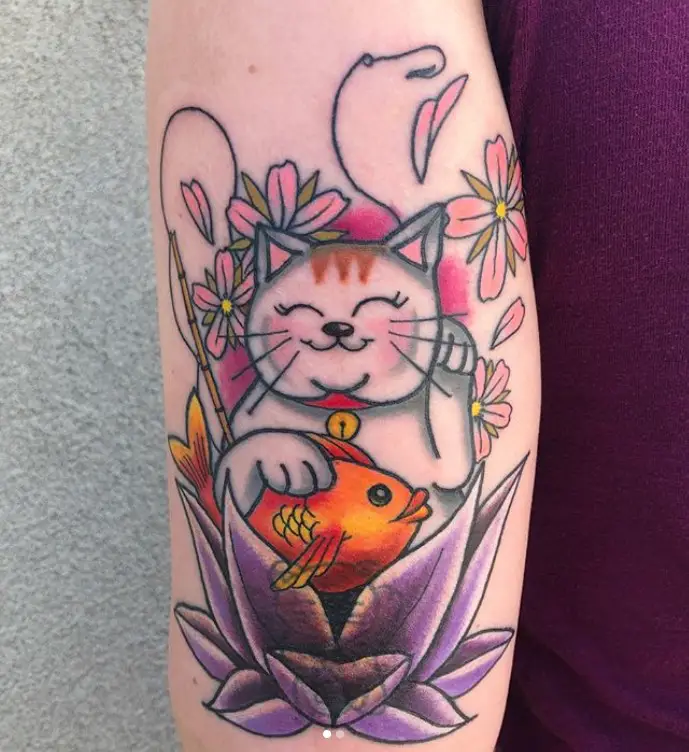 A white Lucky Cat Tattoo on the shoulder