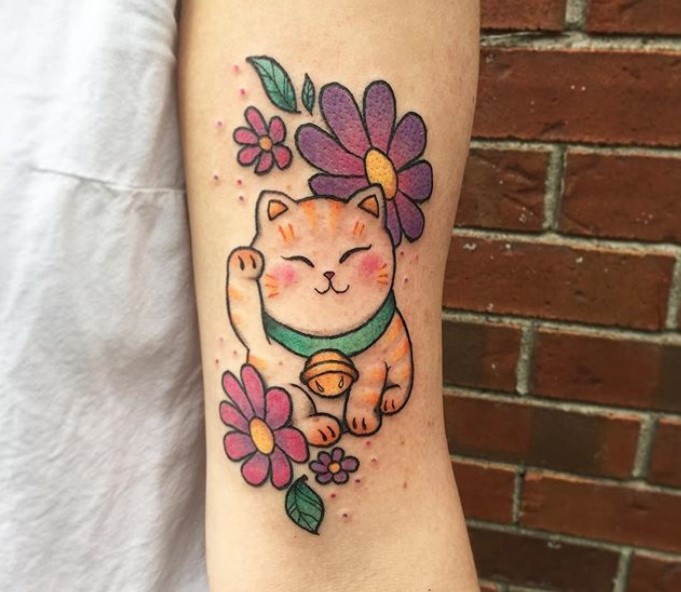 A cute Lucky Cat with purple flowers tattoo on the arm