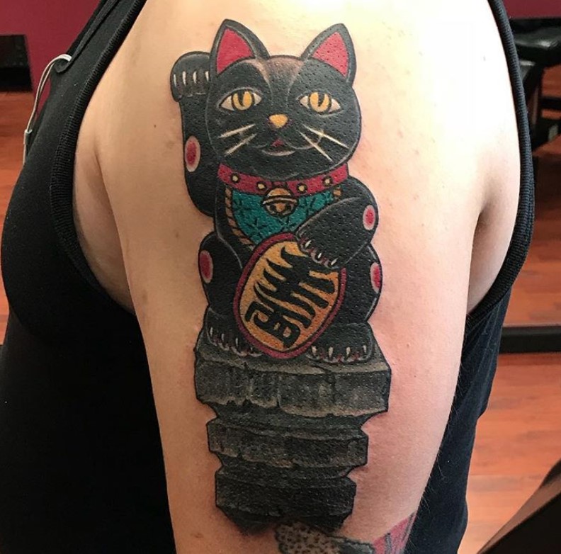 A black Lucky Cat Tattoo on the shoulder
