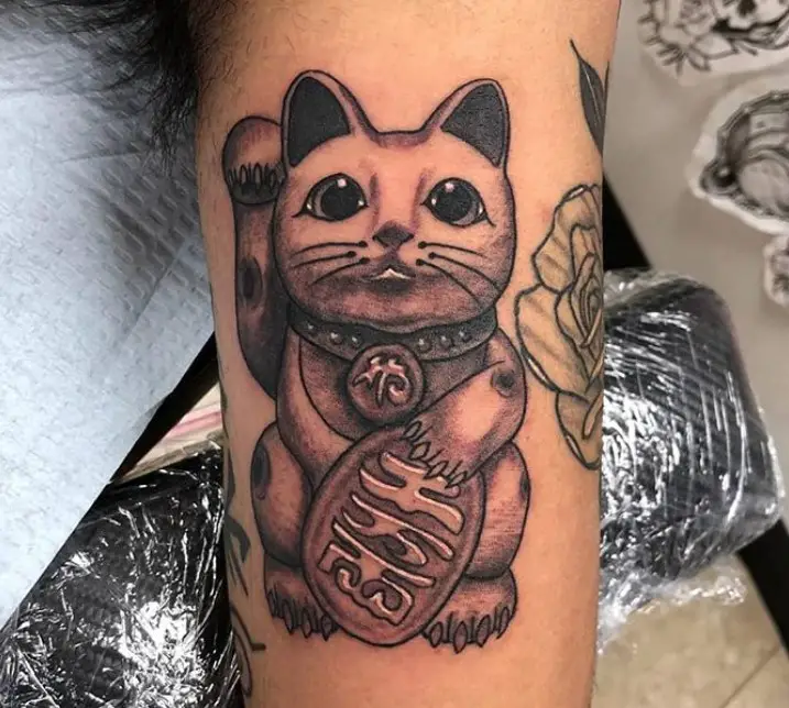 A black and gray Lucky Cat Tattoo on the biceps of a man