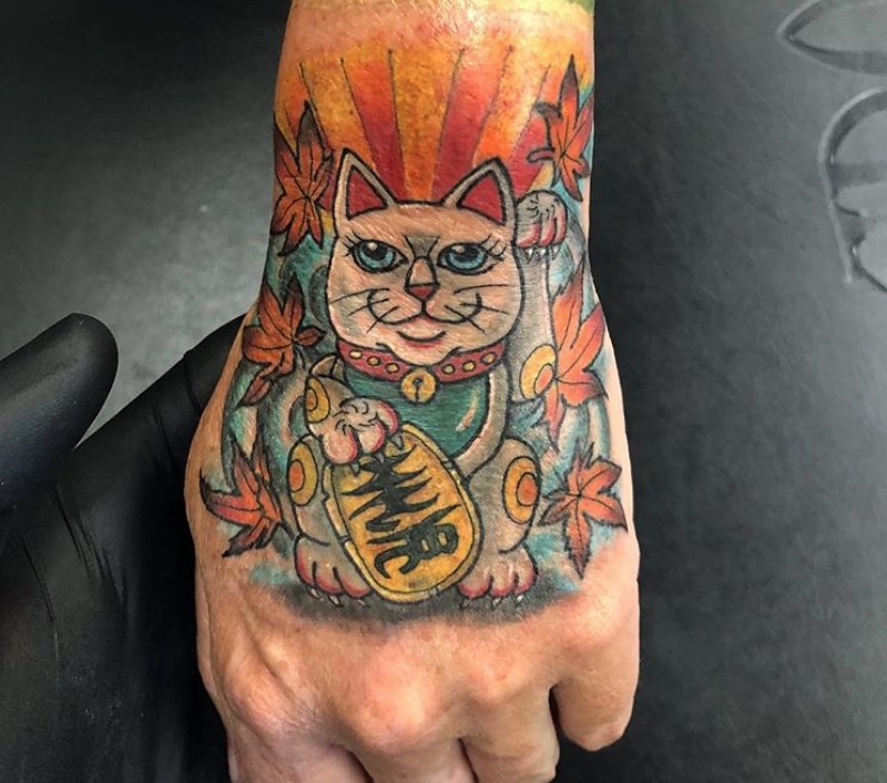 A Lucky Cat with maple leaves tattoo on the hand