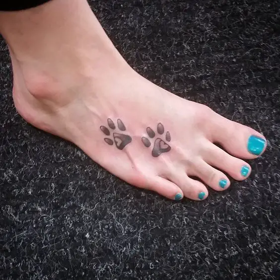 gray paw print with heart inside tattoo on the feet