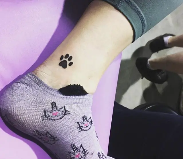 small black paw print tattoo on ankle
