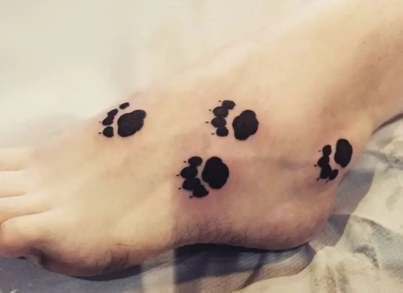 black paw print tattoo on the feet