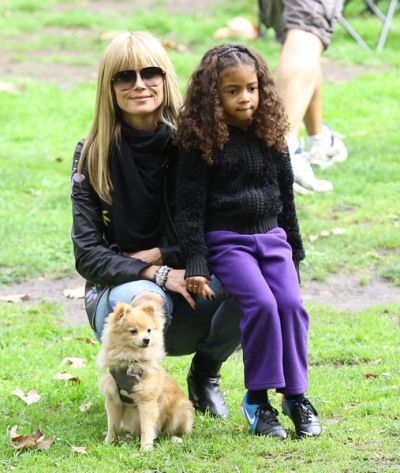 Heidi Klum at the park with her daughter and their pomeranian sitting on the grass