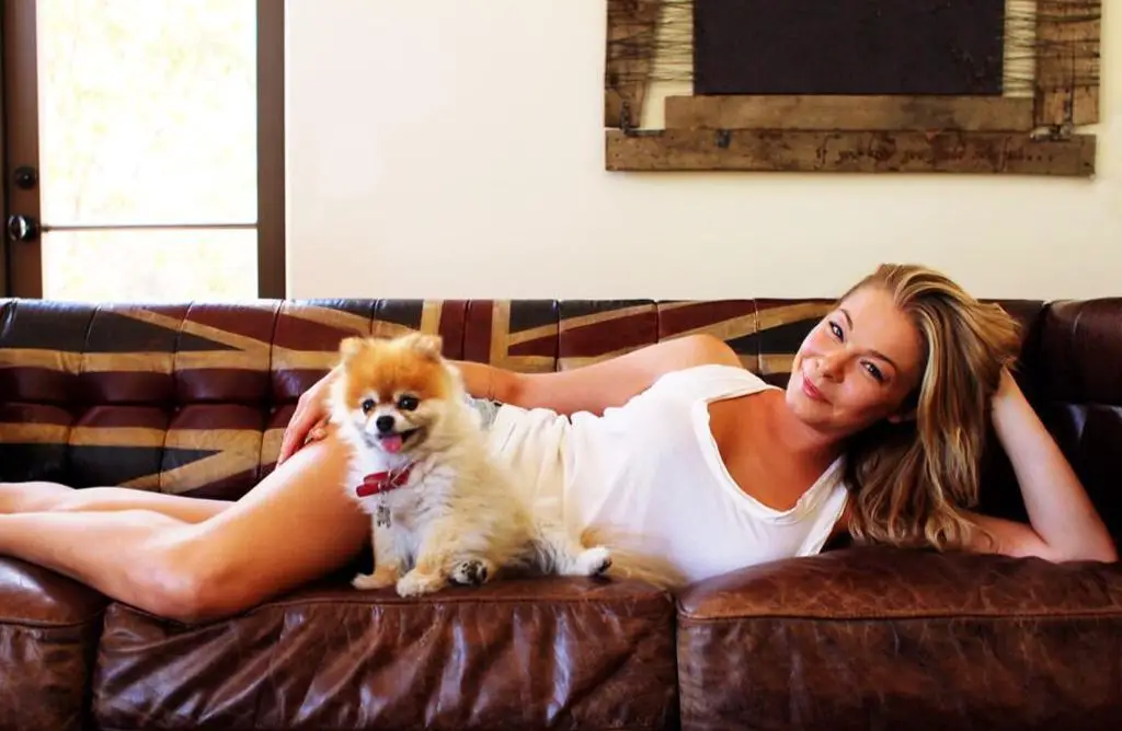 LeAnn Rimes lying on the couch with her Pomeranian