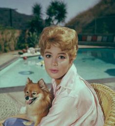 Sandra Dee sitting by the pool with her pomernian on her lap