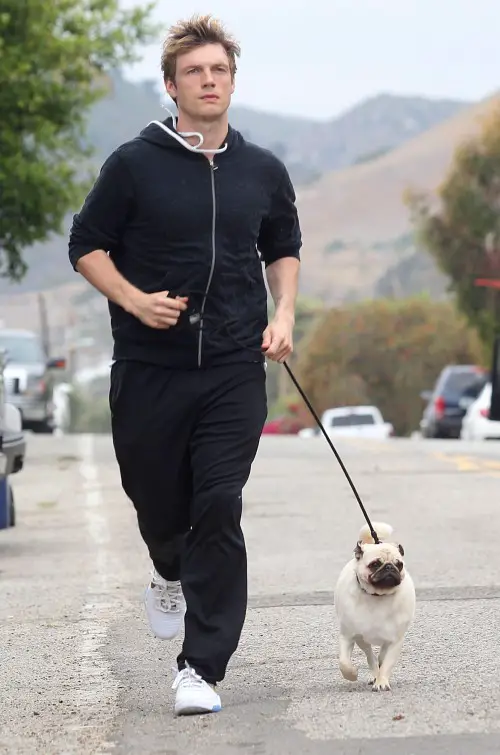 Nick Carter running in the street with his pug on the leash