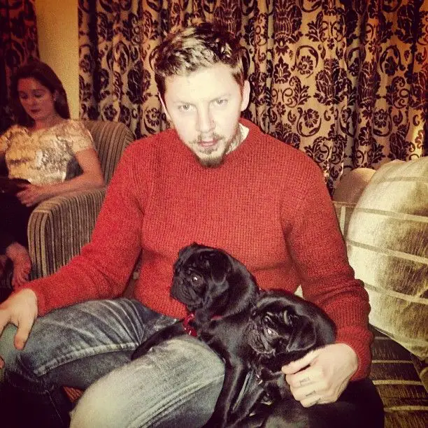Professor Green sitting on the couch with his two black pugs