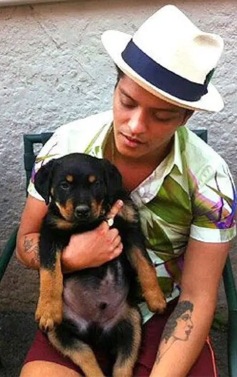 Bruno Mars sitting on the chair with his Rottweiler puppy in his lap