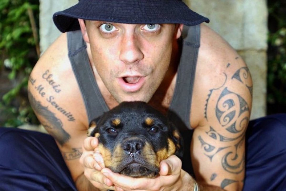 Robbie Williams holding his Rottweiler puppy's face