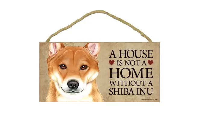 A wooden door sign with the face of a Shiba Inu and with a saying - A house is not a home without a Shiba Inu