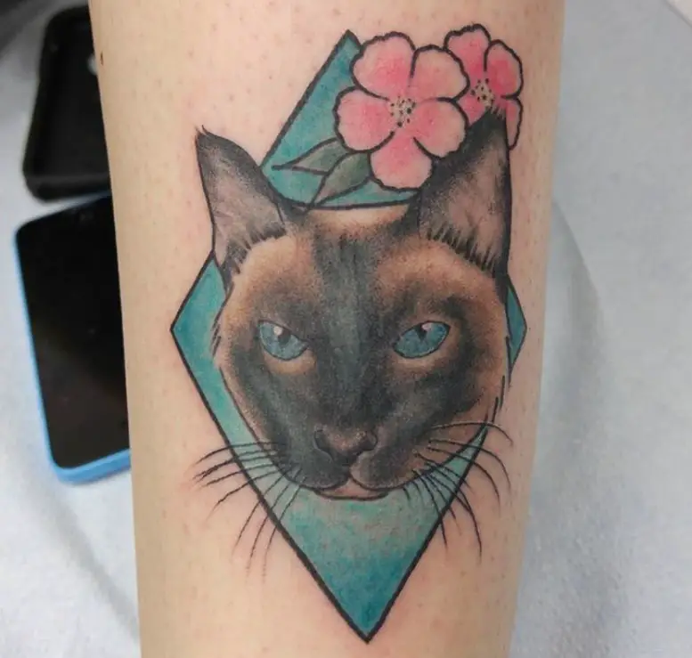 face of a Siamese Cat in a blue diamond with pink flowers on top tattoo