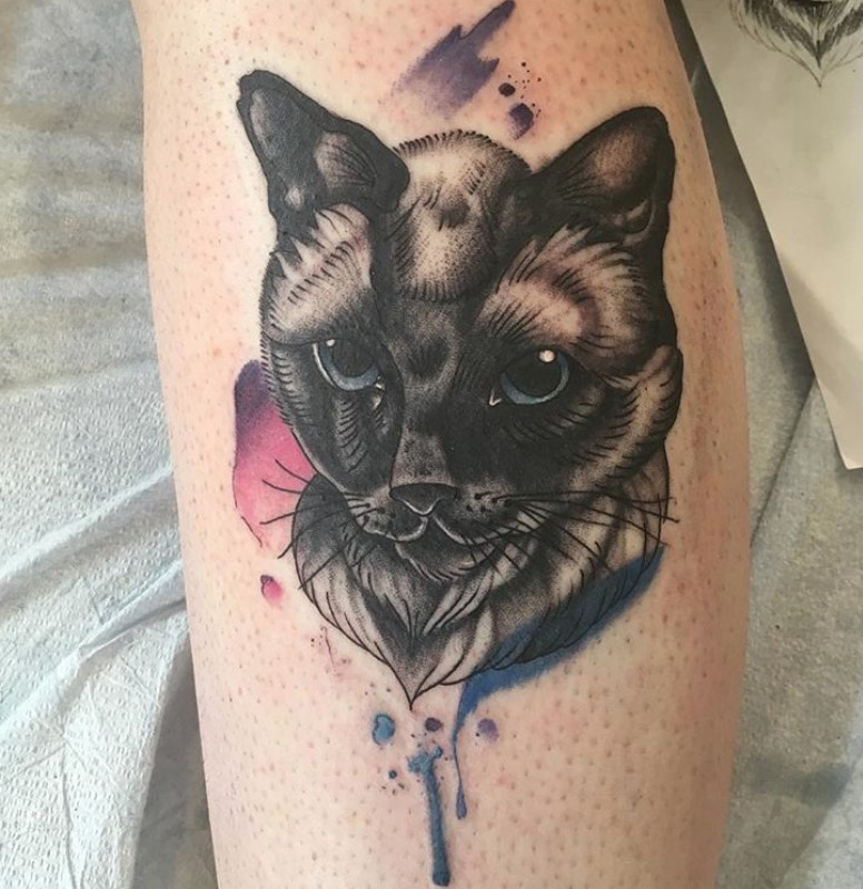 realistic black and gray Siamese Cat with purple, blue, and pink watercolors around it tattoo on the leg