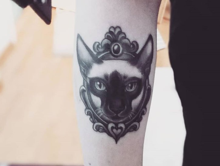 black and gray face of a Siamese Cat in a vintage frame tattoo on the leg