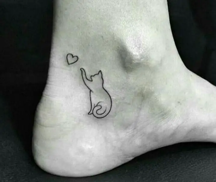 outline of cat grabbing a heart tattoo on the ankle