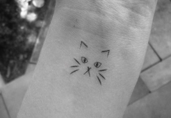 minimalist face of a cat tattoo on the wrist