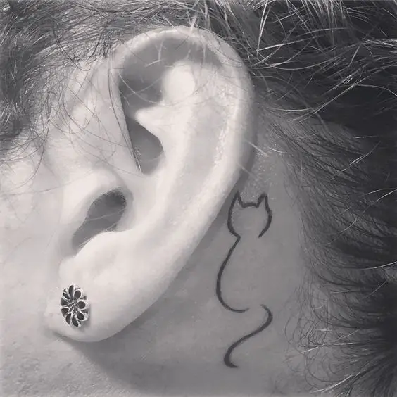 outline of a sitting cat tattoo on the back of the ear